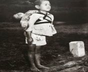 During World War II, a Japanese boy stood in front of a funeral pyre and waited his turn to cremate his little dead brother. The person who took the photograph said, in an interview, that the boy was biting his lips so hard to keep from crying that bloodfrom grani japanese boy