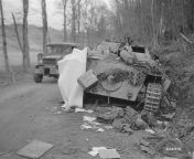 A Dodge from the 26th Infantry Division drives past a knocked out Jagdpanzer 38 (t) on the road to Saarlautern.Next to the rear of the vehicle the body of a member of the crew.Germany, March 18, 1945 from step to the rear 1991